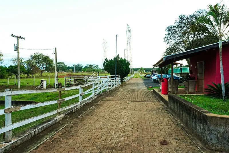 Caminho ao lado da cerca branca com pasto e muito verde